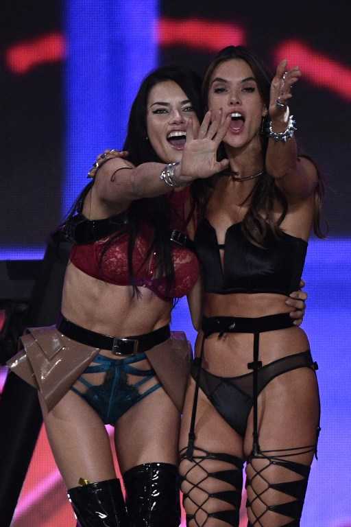 Brazilian model Adriana Lima (L) and Brazilian model Alessandra Ambrosio cheer during the 2016 Victoria's Secret Fashion Show at the Grand Palais in Paris on November 30, 2016. / AFP PHOTO / Martin BUREAU / RESTRICTED TO EDITORIAL USE